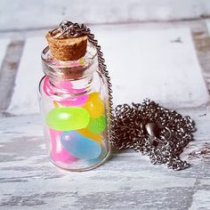 a glass jar filled with lots of different colored candies and a chain attached to it