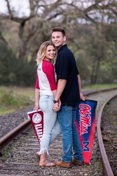 a man and woman standing next to each other on train tracks with their flags in hand