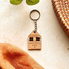 a wooden house keychain sitting on top of a table next to a plant