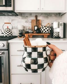 a person holding a mug with cinnamon sticks in it