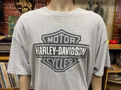 a grey harley davidson t - shirt sitting on top of a wooden table in front of a brick wall