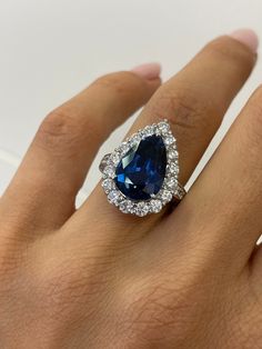 a woman's hand with a blue and white diamond ring on top of it