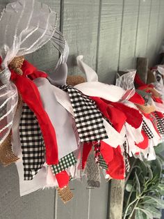 a christmas wreath hanging on the side of a door decorated with red, white and black ribbons