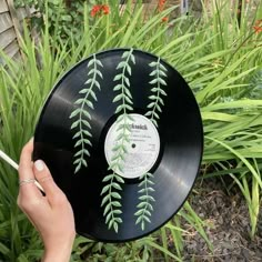 a hand holding a black record with green leaves on it