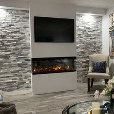 a living room with a fireplace and television mounted on it's wall above a glass coffee table