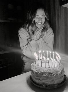 a woman sitting in front of a cake with lit candles