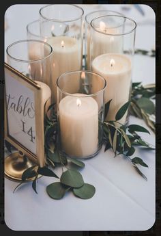 candles are arranged on a table with greenery