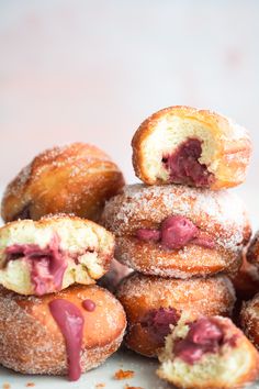 a pile of doughnuts with powdered sugar and jelly filling on the top