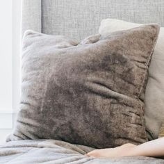 a woman laying on top of a bed next to a brown and white pillow covered in blankets