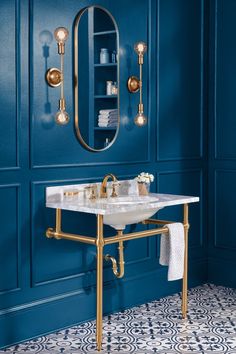 a bathroom with blue walls, gold fixtures and a white sink in front of a mirror