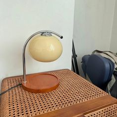 a table lamp sitting on top of a wicker basket next to a backpack and chair