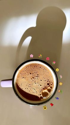 a cup of coffee sitting on top of a table next to a person's shadow