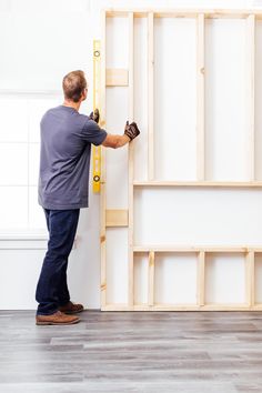 a man is working on the wall in his new home with wood framing and tools