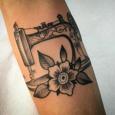 a tattoo on the arm of a woman with a sewing machine and flowers in it