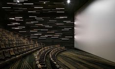 an empty auditorium with rows of seats in front of a projector screen and lights on the ceiling