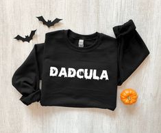 a black sweatshirt with the word dadcula written on it next to some bats