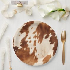 a brown and white plate sitting on top of a table next to utensils