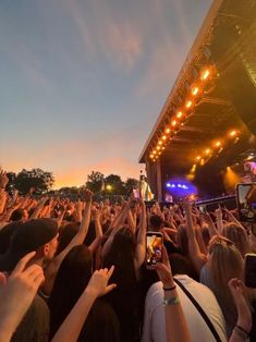 a large group of people at a concert with their cell phones up in the air