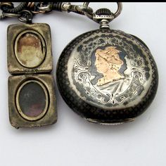 "Antique open face pocket watch, having Swiss movement and 800 silver case with chain and locket charm, decorated with Niello black enamel. Case features gilt depiction of Hermes profile on the back. Locket has two compartments and gilt shield on the front side. c. 1890. Watch runs. This amazing watch is 1 5/8\" in diameter, the chain is 9 3/4\" long. The locket measures 15/16\" long x 3/4\" wide. Total weight is 91.1 grams. EA678." Victorian Medallion Pocket Watch For Formal Occasions, Medallion Shaped Pocket Watch With Chronometer As Gift, Antique Locket Pocket Watch For Formal Occasions, Timeless Engraved Locket Necklace For Formal Occasions, Antique Bronze Engraved Pocket Watch, Antique Engraved Silver Pocket Watch, Antique Bronze Pocket Watch With Locket, Antique Pocket Watch With Locket, Timeless Pocket Watch With Locket For Collectors