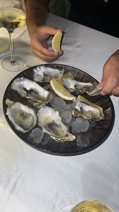 a plate full of oysters with lemon wedges