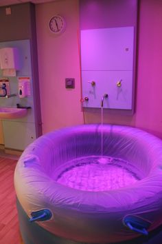 an inflatable bathtub is lit up with purple lights and water spouting from the faucet