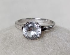 a close up of a ring with a diamond on the top and bottom, sitting on a white surface