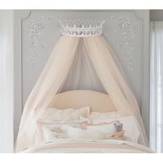 a bed with a white canopy over it's headboard and pillows on top of it