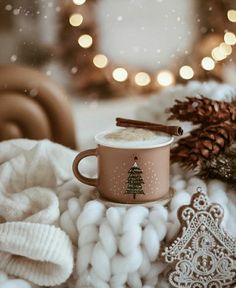 a cup of hot chocolate sitting on top of a pile of white balls next to a christmas tree ornament