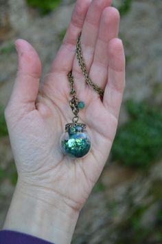 PLEASE read my shop announcement before placing an order so you know what to expect right now. Plus, when ordering from outside Europe, don't forget to provide a phone number for the courier to ensure the fastest and smoothest delivery. Wizard of Oz inspired necklace featuring a magical glass orb enclosing some emerald green iridescent glitter in various sizes and a few amazing emerald faceted crystals. The glass ball, in a charming Vintage style, dangles from a quatrefoil shape adorned with a g Whimsical Green Nickel-free Jewelry, Green Nickel-free Pendant Charm Necklace, Green Pendant Necklace As Keepsake, Green Pendant Necklace For Keepsake, Whimsical Green Round Jewelry, Whimsical Green Jewelry For Gifts, Green Spiritual Jewelry For Party, Spiritual Green Round Pendant Crystal Necklace, Spiritual Green Crystal Round Pendant Necklace