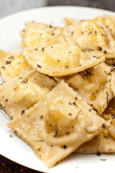 a white plate topped with ravioli covered in cheese