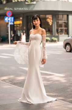 a woman in a white wedding dress is standing on the street with her arms outstretched