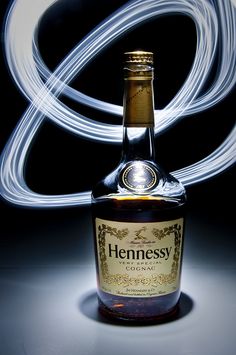 a bottle of hennesy brandy sitting on top of a table next to a light painting