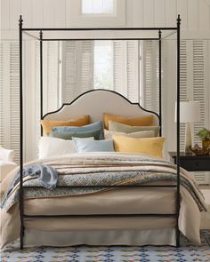 a four poster bed with pillows and blankets on it