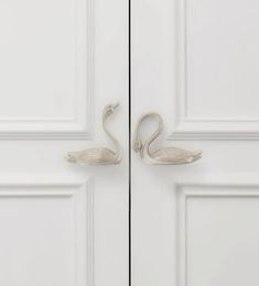 two swans are standing next to each other in front of white door handles and doors