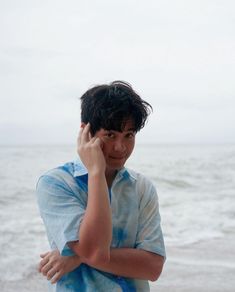 a young man is talking on his cell phone at the beach