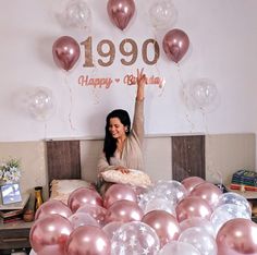 a woman sitting on top of a bed surrounded by balloons