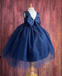 Our enchanting Ankle Length flower girl dresses are sure to turn heads! Bodice is made of Navy Blue satin, waist consists of a matching sowed in sash (NOT DETACHABLE) The back of the dress has an open deep V-Back with a hidden zipper, followed by a detachable bow. The skirt has 4 tulle layers for fullness, the top layer of tulle consists of pearls. The dress has 2 layers of lining with crinoline. This dress is perfect for any occasion!  Dress Is Pictured with a petticoat NOT INCLUDED https://www.etsy.com/listing/1305138635/white-ankle-length-petticoat-wedding?click_key=50d449c187c9e82c565249da914d7ed38b32b9f7%3A1305138635&click_sum=17db9314&ref=shop_home_active_2 Visit our store, more items to come!  https://www.etsy.com/shop/LittledarlnBoutique?ref=profile_header CUSTOM MEASUREMENTS AVAIL Navy Blue Toddler Dress, Flower Girl Blue Dresses, Elegant Blue Princess Dress With Bow, Blue Princess Dress With Bow For Dress-up, Blue Princess Tutu Dress With Bow, Princess Style Blue Tutu Dress With Bow, Blue Princess Dress With Bow, Princess Style Blue Ball Gown For Bridesmaid, Navy Blue Flower Girl Dresses