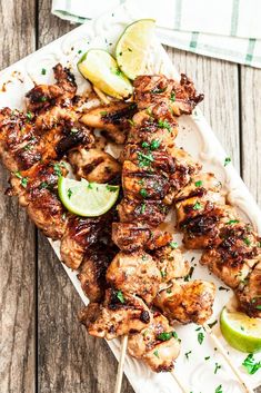 grilled chicken skewers with lemon wedges and parsley on a white plate