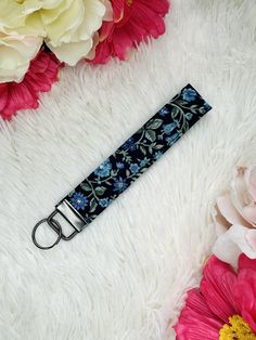 a blue flowered umbrella strap laying on top of a fluffy white blanket next to flowers