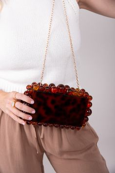 Let your personality shine through with our statement making Cava Clutch! Featuring a detachable gold chain, easily transforming it into a shoulder purse or crossbody for versatile styling options. Own the spotligth wherever you go! Acrylic 8.75"W x 5.25"H Removable Gold Chain Colors may vary with different viewing devices. Versatile Brown Rectangular Clutch, Versatile Brown Shoulder Bag With Chain Strap, Chic Brown Clutch With Chain Strap, Trendy Brown Clutch, Brown Chain Clutch Shoulder Bag, Trendy Crossbody Clutch With Chain, Trendy Brown Clutch For Party, Brown Crossbody Clutch With Chain Strap, Chic Brown Shoulder Bag With Gold Chain