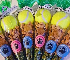 four tennis balls are wrapped in plastic bags with dog paw prints on the top and bottom