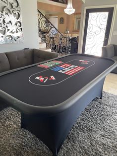 a black pool table in the middle of a living room with grey carpet and stairs