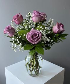 a vase filled with purple roses and baby's breath