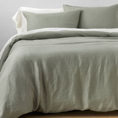 an unmade bed with green sheets and pillows