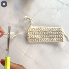 the crochet piece is being worked on with scissors