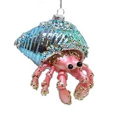 a pink octopus ornament hanging from a silver chain on a white wall with blue beads