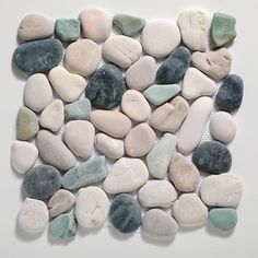 several different colored rocks are arranged in a square shape on a white surface, including one green and one blue