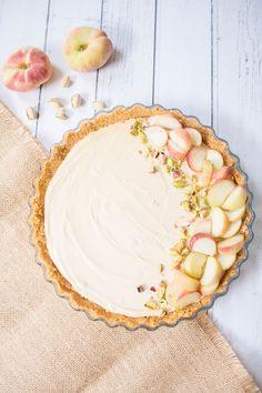 an apple pie with white frosting and sliced apples on the table next to it