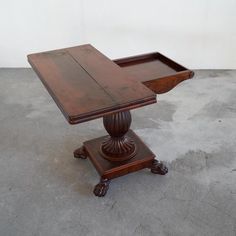 an old wooden table with two trays on it's legs, sitting on concrete