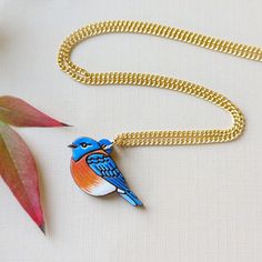 This adorable bluebird necklace is inspired by both the Eastern and Western Bluebird with their unforgettable bright blue wings and round bodies. This original design is digitally illustrated and etched on cherry wood, then delicately hand-painted in hues of blue, white, and orange. Super lightweight and minimalist, this necklace makes a great gift for bird lovers and is a mini work of art! Option 1: Gold Chain This necklace comes with a 17" 24k gold-plated brass dainty curb chain with a lobster Western Bluebird, Blue Wings, Kraft Gift Boxes, White And Orange, Wood Necklace, Gift Card Shop, Wooden Jewelry, Cherry Wood, Bird Lovers